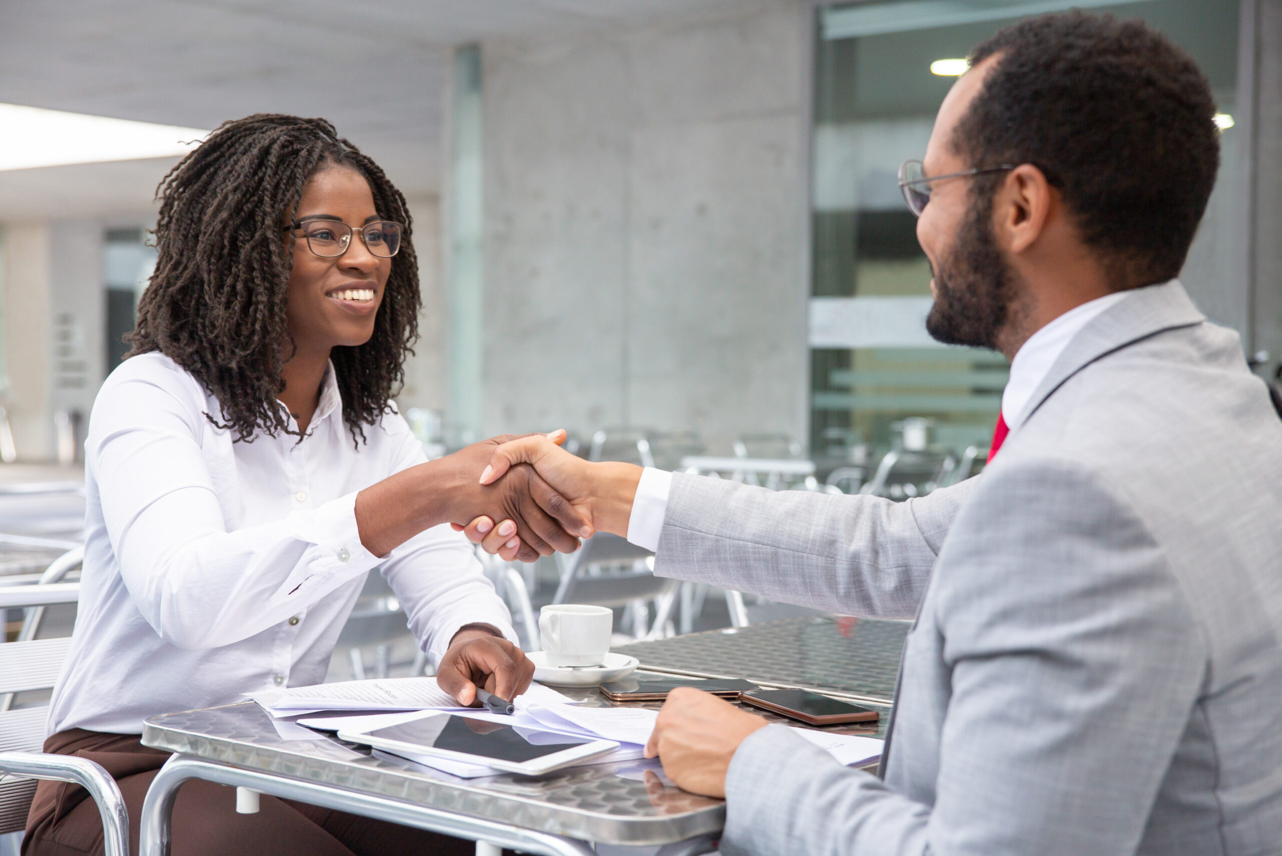 Smiling businesswoman shaking hands with partner. Cheerful businesspeople reaching agreement. Handshake concept